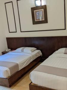 a bedroom with two beds and a picture on the wall at Serene Holiday Chalet with pool in a quiet enclave in Kampong Alor Gajah