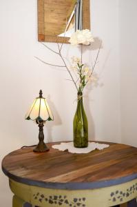 una mesa con una lámpara y un jarrón con flores. en Kenderhordó Pihenőház, en Zánka