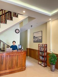un hombre sentado en un mostrador en una biblioteca con un portátil en Phúc Đức Hotel, en Thanh Hóa