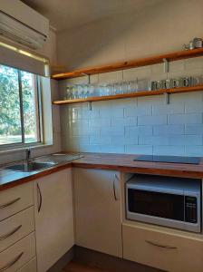 a kitchen with a stove top oven and a microwave at Restaway Holiday Units in Porepunkah