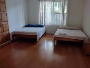 two beds in a room with wooden floors and a window at Finca Villa Hailey in Cali +12 photos