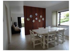 une salle à manger avec une table et des chaises blanches dans l'établissement Guarujá, apartamento a 100 metros da praia da enseada., à Guarujá