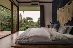 une chambre avec un grand lit et une grande fenêtre dans l'établissement 3 Bedrooms Tropical Modernism Rice Field and Jungle, à Ubud 71 autres photos