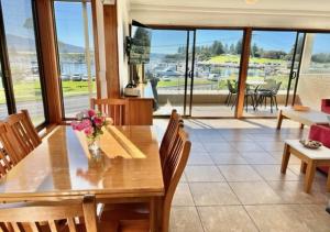a dining room with a wooden table with flowers on it at Bermagui Stays - 2 bedroom Apartment - Amazing views & location in Bermagui