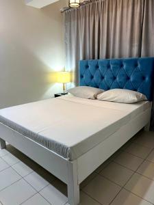 a bed in a bedroom with a blue headboard at LuxeCara Guest House in Lipa