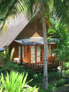uma casa de madeira com um alpendre e palmeiras em Green Papaya Beach Resort, Koh Phangan em Salad Beach