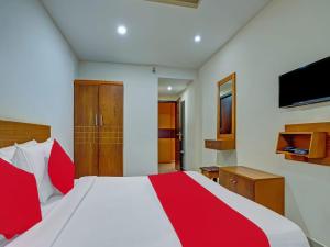 een slaapkamer met een rood en wit bed en een televisie bij Marhaba Tourist Home in Kozhikode