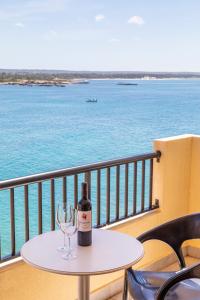 a bottle of wine on a table with a wine glass at Apartamentos Piza in Colonia Sant Jordi