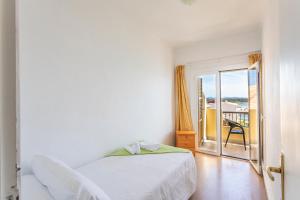 a white bedroom with a bed and a balcony at Apartamentos Piza - Grupo Berna in Colònia de Sant Jordi