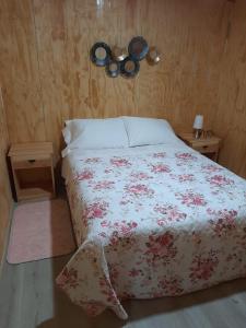 1 dormitorio con 1 cama con colcha de flores en CABAÑAS DON EDUARDO, en Melipeuco