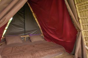 Bett in einem roten und grünen Zelt in der Unterkunft Batan Nyuh Retreat in Gianyar