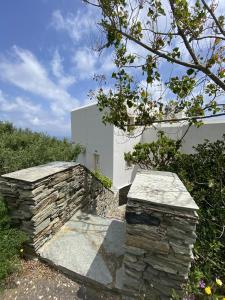 a stone retaining wall next to a building at Andros Vineyard house with sea view in Sinétion