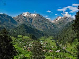 a village in a valley with mountains in the background at Kashmir Outlook Adventures in Pahalgām