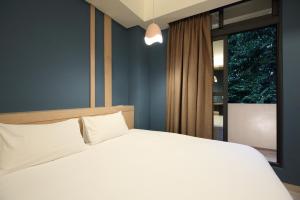 a bedroom with a white bed and a window at Pin House in Hualien City