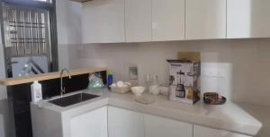 a kitchen counter with a sink and white cabinets at 米米民宿 in Kluang