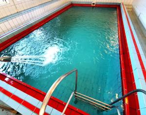 a swimming pool with blue water in a red tub at Hotel Montana - Covasna in Covasna