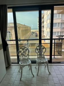 dos sillas sentadas frente a una ventana en appartement met zeezicht, en Ostende
