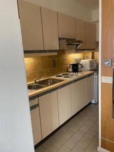 cocina con armarios blancos, fregadero y microondas en appartement met zeezicht, en Ostende