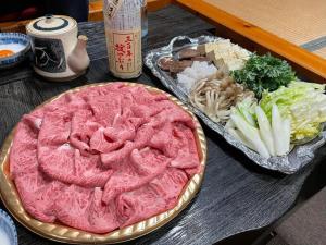 una mesa cubierta con una pizza rosa y una bandeja de verduras en 趣味複合施設イイトコ 