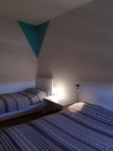 um quarto com duas camas e uma luz na parede em 6daNoi bis em Ivrea