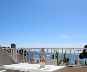a table with two wine glasses on a balcony at Les Alcyons in Le Lavandou