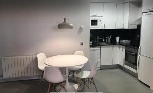 cocina blanca con mesa blanca y sillas en Apartamento con encanto en Igualada