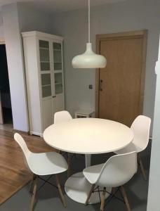 a white dining room table with white chairs and a light fixture at Apartamento con encanto in Igualada