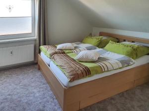 a bedroom with a large bed with green pillows at Ferienwohnung Reins in Neustadt in Holstein