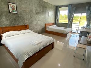 1 dormitorio con 2 camas y ventana en Eden House Resort, en Nakhon Nayok