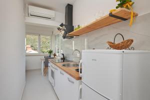 a kitchen with a white refrigerator and a sink at Apartments Micika in Cavtat