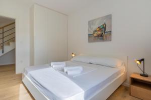 a white bed in a room with a painting on the wall at Best Sea View Apartment in Cres