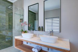 a bathroom with two sinks and a mirror at Knysna Hollow Country Estate in Knysna