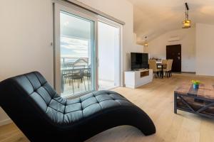 a living room with a black leather chair and a living room at Best Sea View Apartment in Cres
