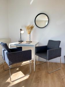 a desk with two chairs and a table with a mirror at Hegau Boardinghouse in Singen
