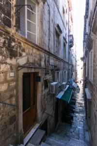 an alley in an old building with benches on it at Rooms Fausta Old Town in Dubrovnik
