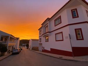 a house on a street with a sunset in the background at Guesthouse Releash Aljezur in Aljezur