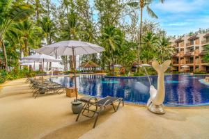 a pool at a resort with chairs and an umbrella at Best Western Premier Bangtao Beach Resort & Spa in Bang Tao Beach