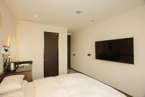 a bedroom with a white bed and a flat screen tv at Hotel The Designers Hongdae in Seoul