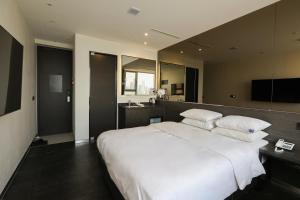 a bedroom with a large white bed and a bathroom at Hotel The Designers Hongdae in Seoul