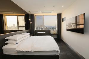 a bedroom with a large white bed with a large window at Hotel The Designers Hongdae in Seoul