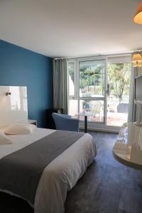 a hotel room with a bed and a view of a patio at Les Alcyons in Le Lavandou