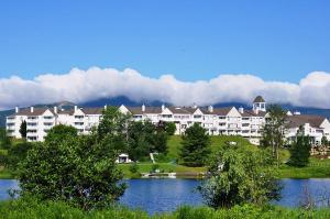 duży budynek apartamentowy z jeziorem przed nim w obiekcie Manoir des Sables Hôtel & Golf w mieście Magog-Orford