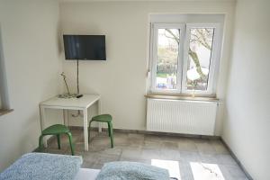 1 dormitorio con 2 sillas verdes, mesa y ventana en Greenhome Lörrach -Ihre Unterkunft im 3-Ländereck-, en Lörrach