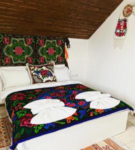 Una cama con una manta colorida y almohadas. en Casa Grai Moroșănesc en Breb