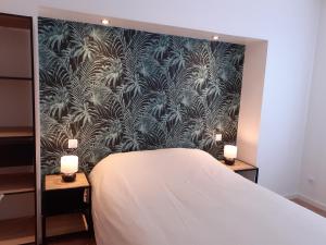 1 dormitorio con cama y pared con papel pintado en KALEE APPARTEMENT T2, en Lanester
