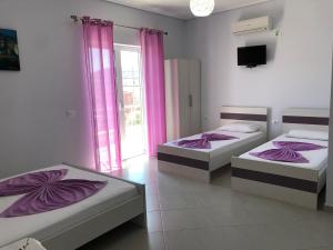 duas camas num quarto com cortinas cor-de-rosa em GB Rooms em Ksamil