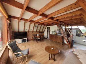 a large living room with wooden ceilings and a staircase at Chalet de vacances au bord de mer VER SUR MER in Ver-sur-Mer