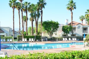 a swimming pool with palm trees in a resort at Desert Breezes Resort in Palm Desert +12 photos