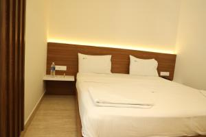 1 dormitorio con 1 cama grande y cabecero de madera en Hotel Amoha, en Palani