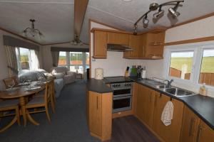a kitchen with wooden cabinets and a table in a room at The Lodge in Amlwch